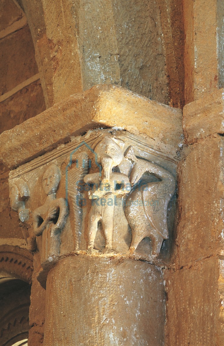 Capitel de la nave, con músico tocando un instrumento de viento, ave y mujer con brazos en jarras