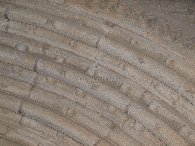 Detalle de las arquivoltas de la portada con decoración de bolas y estrellas