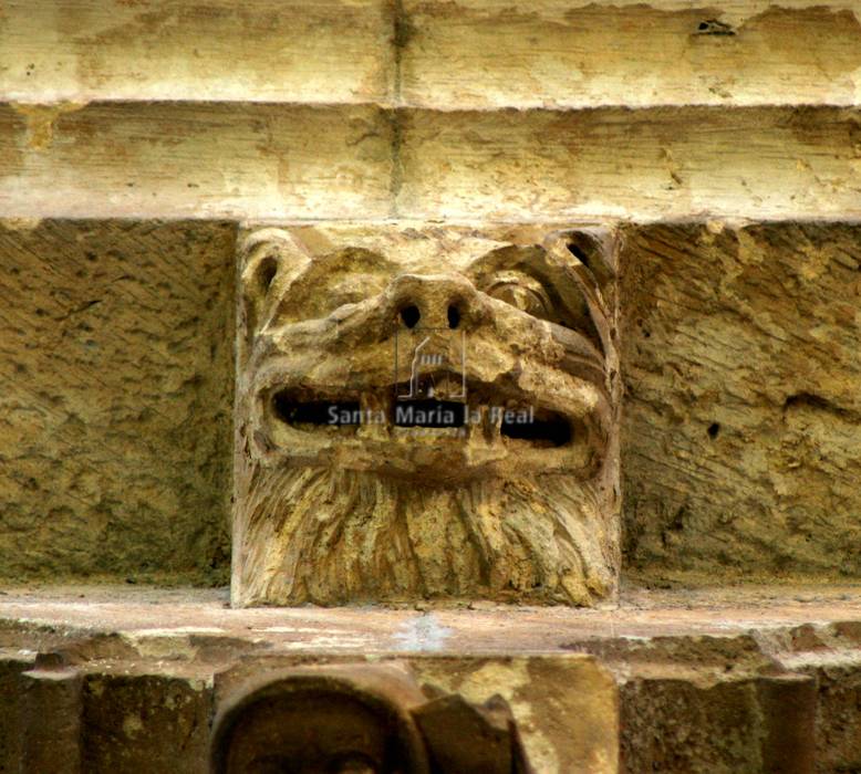 Canecillo de cabeza monstruosa en diagonal  y sonriente,en el ábside central