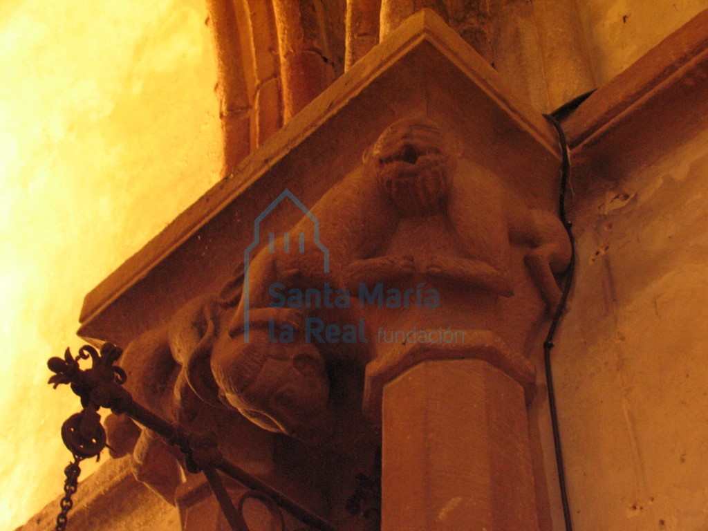 Capiteles de las columnas pareadas del presbiterio. Cabeza humana y dos parejas de monos con una única cabeza que sostienen entre sus garras otras figurillas humanas