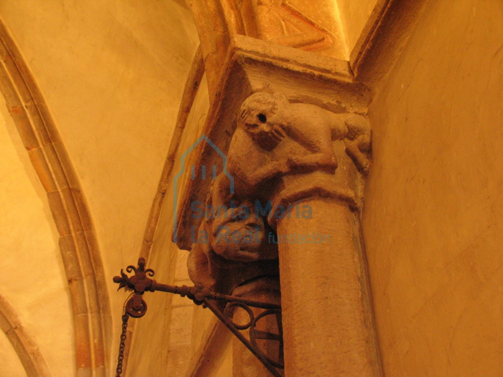 Capiteles de las columnas pareadas del presbiterio. Cabeza humana y dos parejas de monos con una única cabeza que sostienen entre sus garras otras figurillas humanas