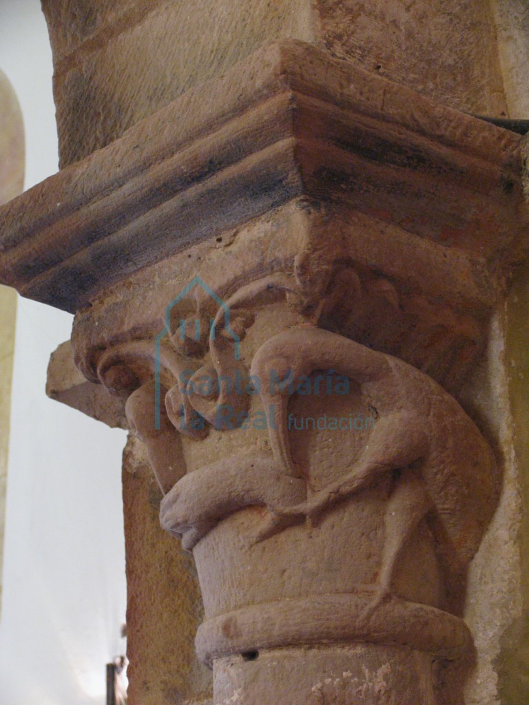 Capitel izquierdo del arco triunfal decorado con dos aves picoteando un bicho