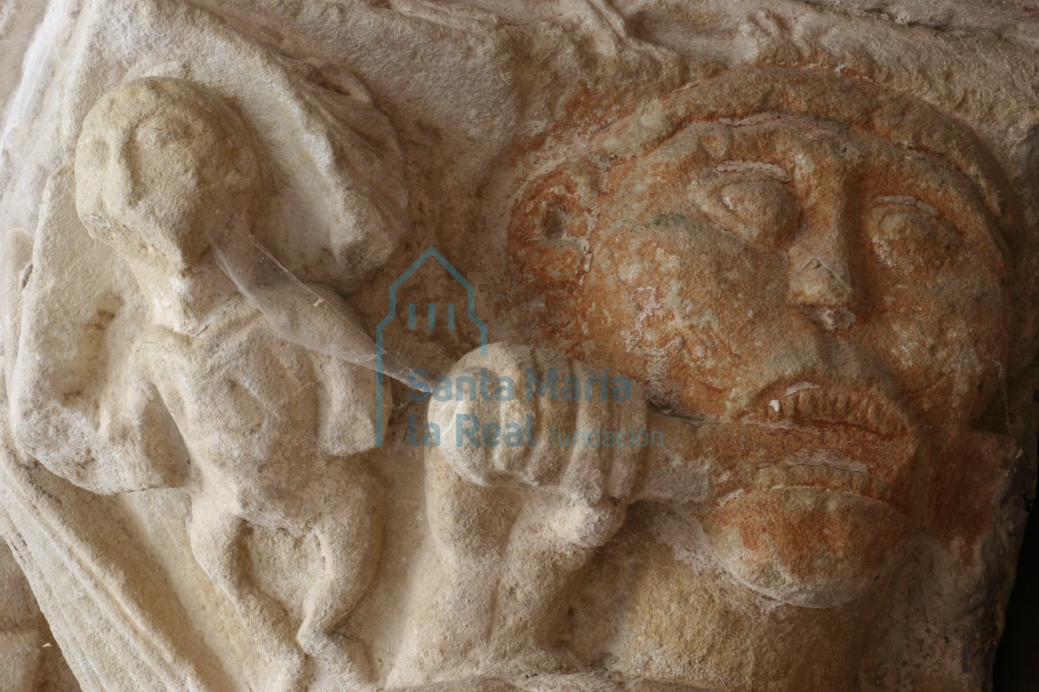 Detalle del capitel del lado izquierdo de la portada occidental. Figura humana y un rostro que introduce en su boca un objeto que acerca con su mano Detalle del capitel del lado izquierdo de la portada occidental. Figura humana y un rostro que introduce en su boca un objeto que acerca con su mano