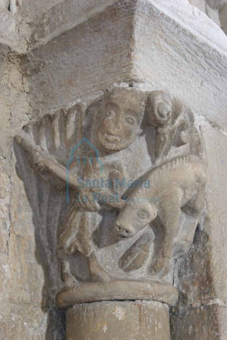 Capitel del arco de comunicación entre la capilla mayor y la capilla del Evangelio. Hombre que alancea un jabalí bajo dos volutas