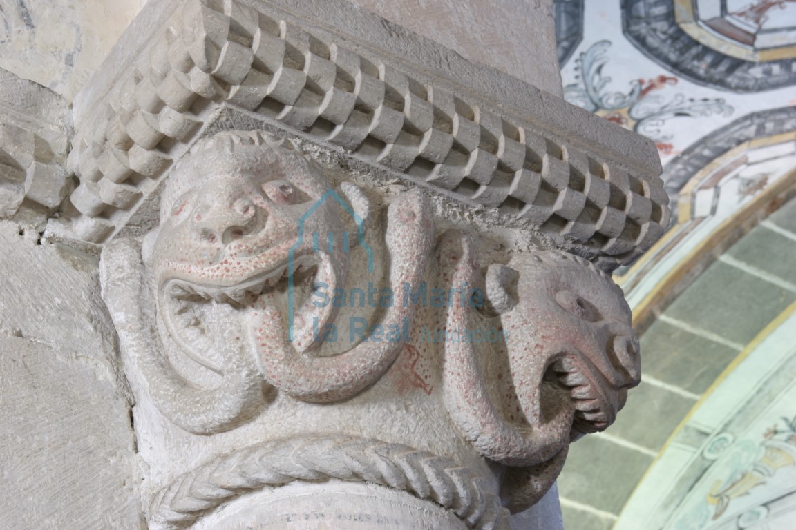 Capitel de la arquería absidal. Dos cabezas monstruosas de cuyas bocas salen dos sierpes