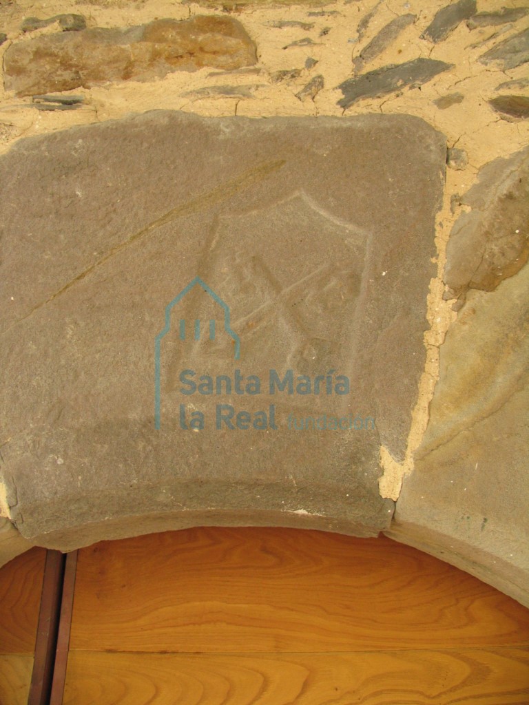 Talla de un escudo en la clave del arco de la portada meridional