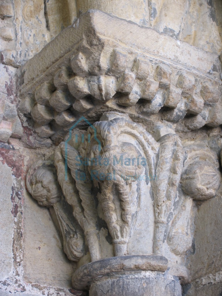 Capitel del lado derecho de la portada románica. Ramas de palma de las que cuelgan bolas