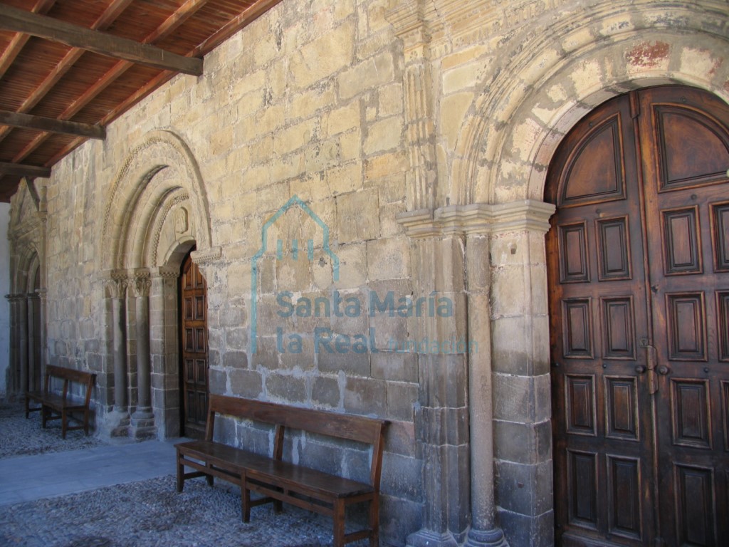 Portada románica flanqueada por otras dos puertas monumentales de factura neoclásica