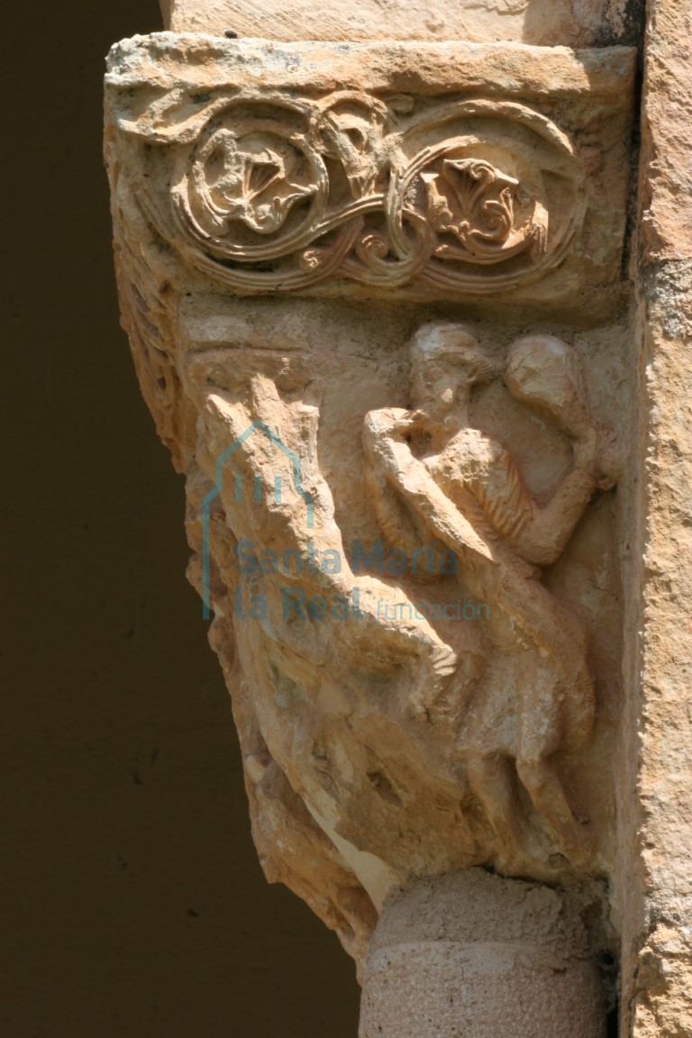 Capitel que representa a una hombre portando una maza y le rodea una serpiente, en el pórtico