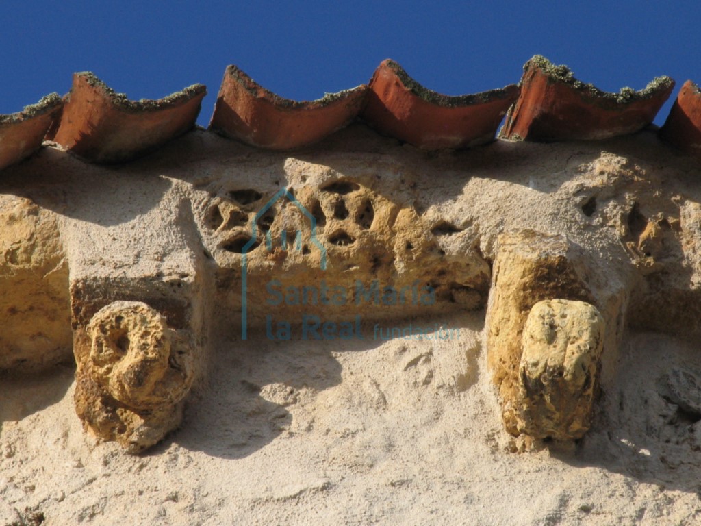 Detalle de la cornisa decorada con una doble cinta vegetal acanalada que va formando círculos dentro de los cuales se inscriben estrellas de cuatro puntas. Y canecillos.