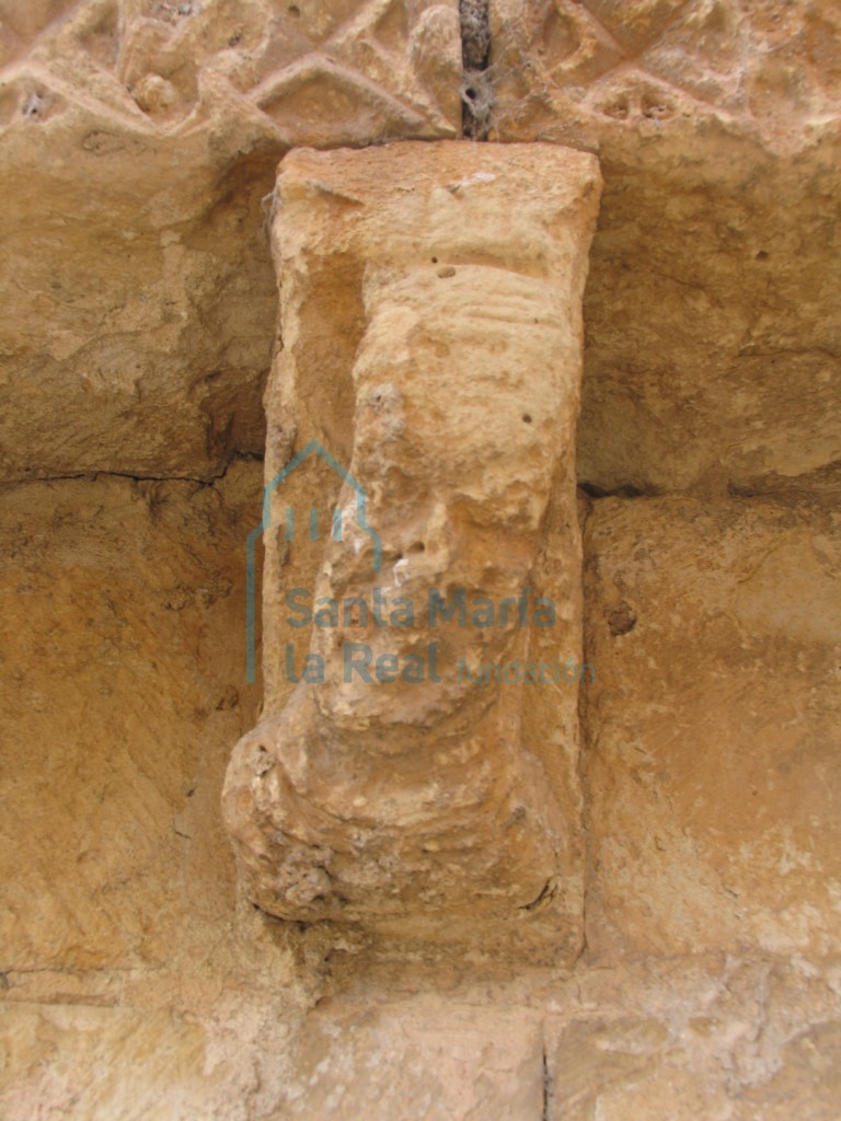Canecillo en la cornisa de la galería, con decoración figurada que representa a un personaje burlón
