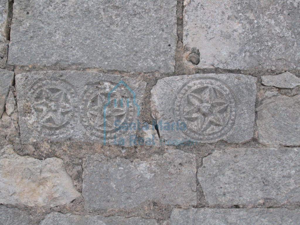 Vista de dovelas decoradas con hexapétalas reutilizadas en el muro del pórtico cegado