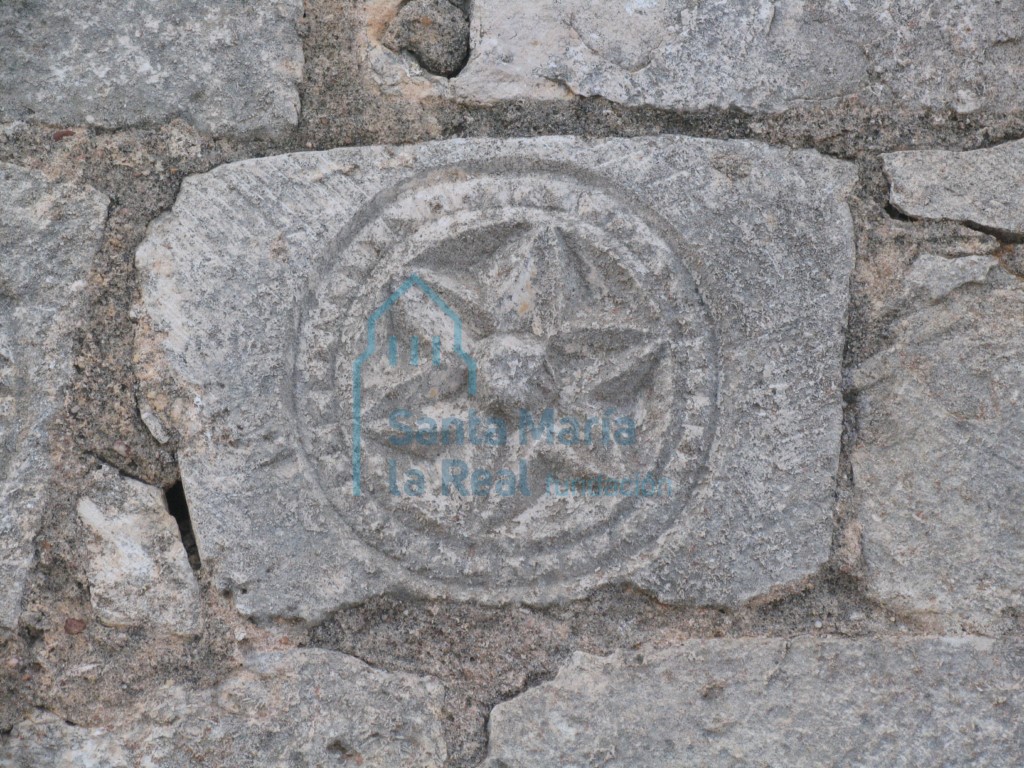 Vista de dovela decorada con hexapétalas reutilizada en el muro del pórtico cegado