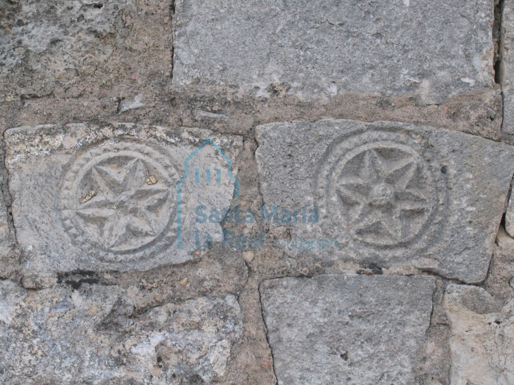 Vista de dovelas decoradas con hexapétalas reutilizadas en el muro del pórtico cegado