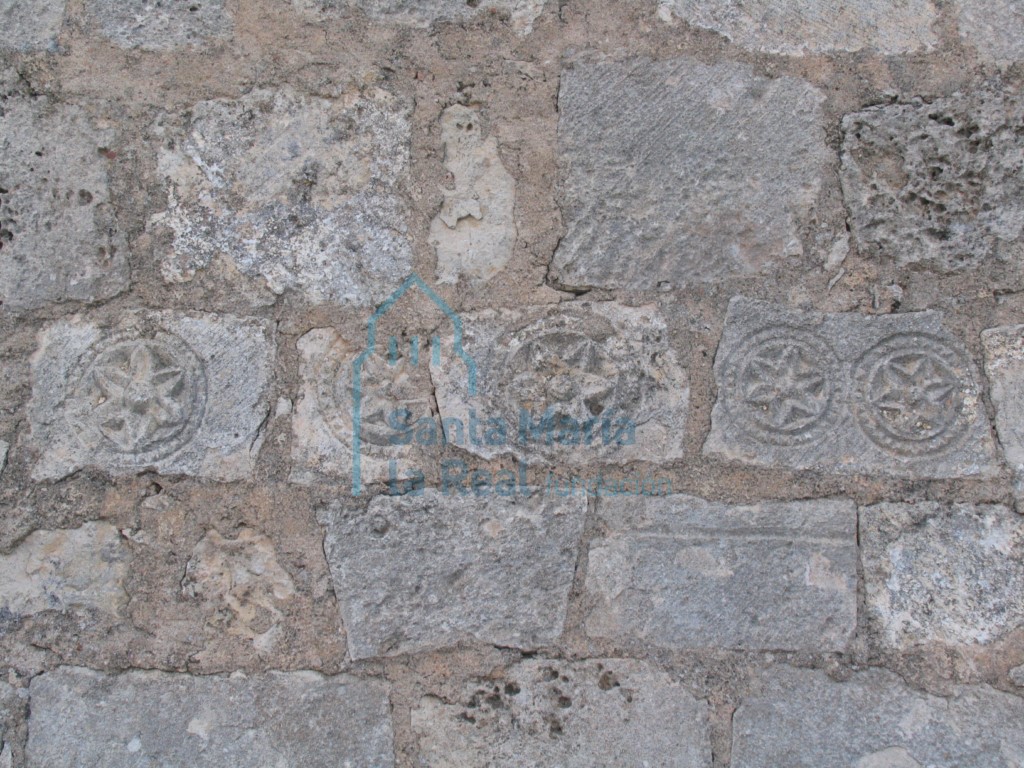 Vista de dovelas decoradas con hexapétalas reutilizadas en el muro del pórtico cegado