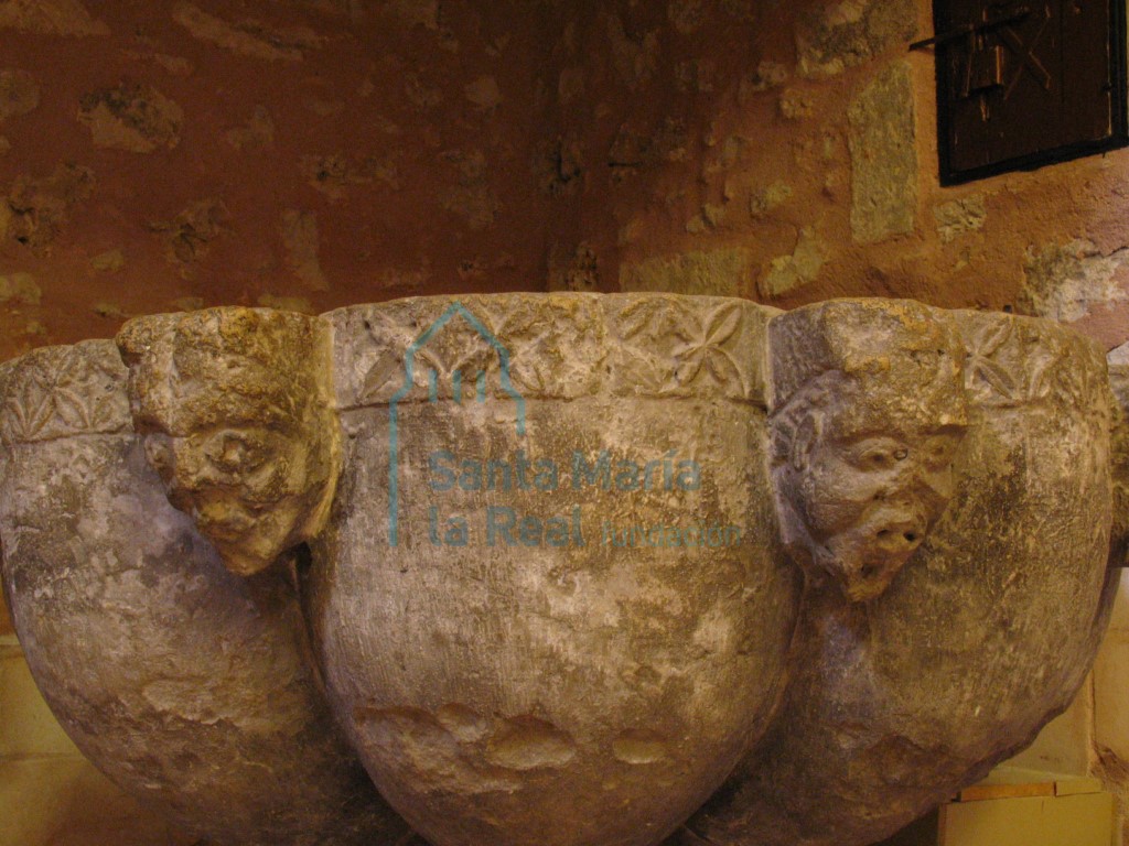 Detalle de la pila bautismal. Gallones y cabecitas humanas intercaladas