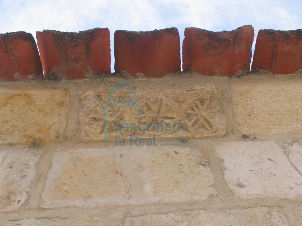 Decoración de rosetas de cinco y seis pétalos insertadas en clípeos en la cornisa
