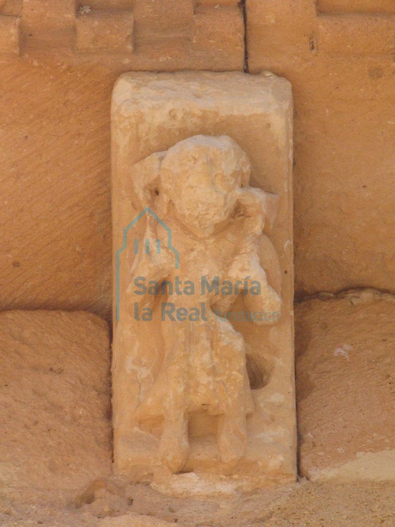 Canecillo de una figura humana portando un animal en los hombros, en la cabecra