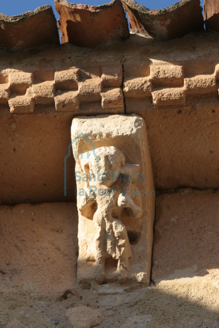 Canecillo de una figura humana portando un animal en los hombros, en la cabecera