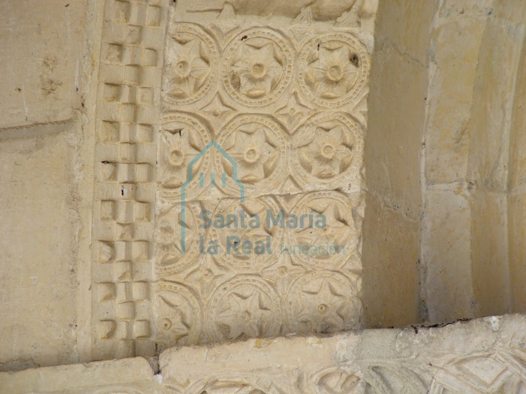 Decoración de florones hexapétalos inscritas en círculos en la arquivolta exterior de la portada meridional