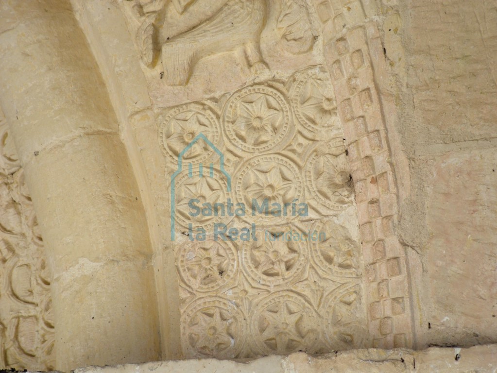 Decoración de florones hexapétalos inscritas en círculos en la arquivolta exterior de la portada meridional