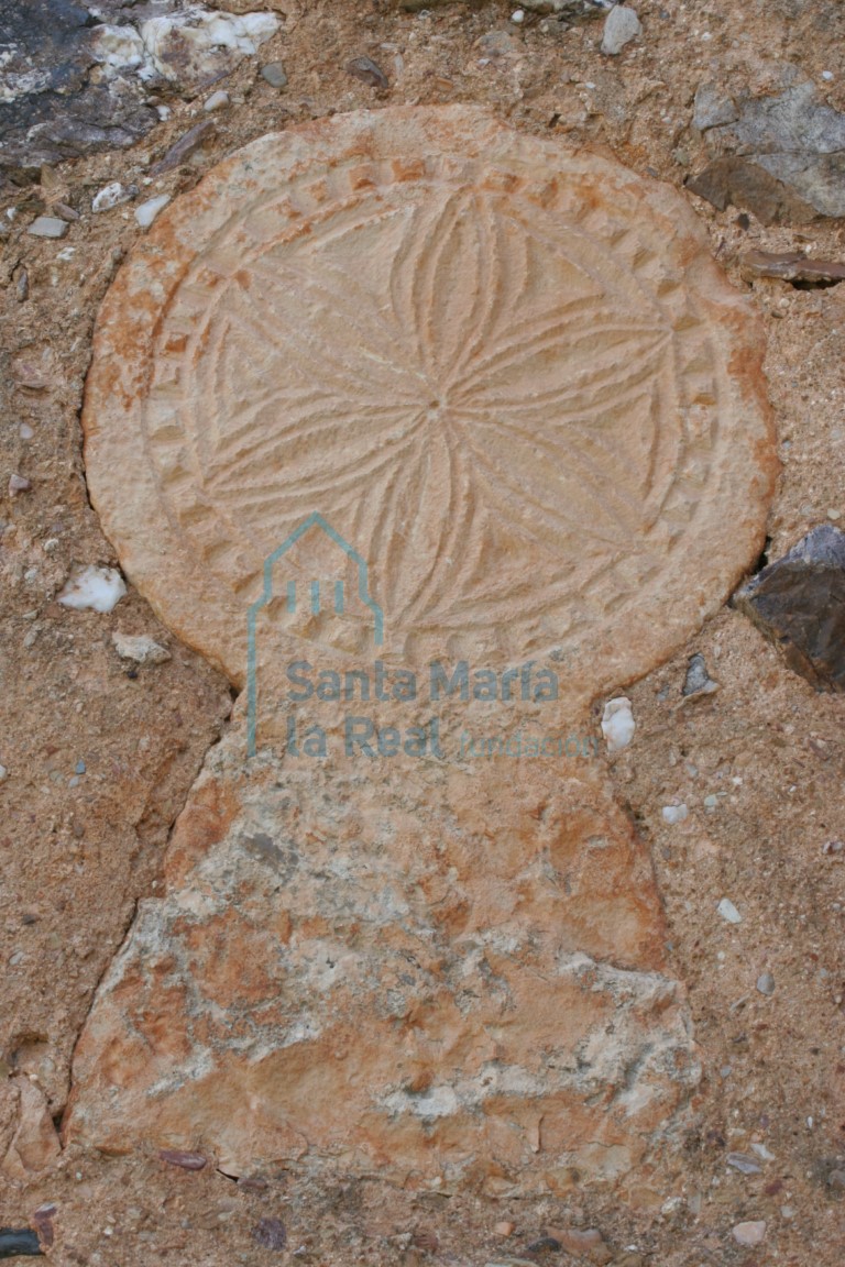 Estela con flor hexapétala inscrita en un círculo, reaprovechada en el muro de la espadaña