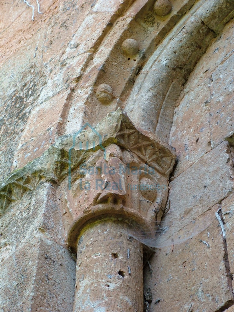 Detalle de la aspillera del ábside, en el que se observan la decoración con bolas, capitel ornamentado por una hoja muy esquemática en cuyo centro hay una bola