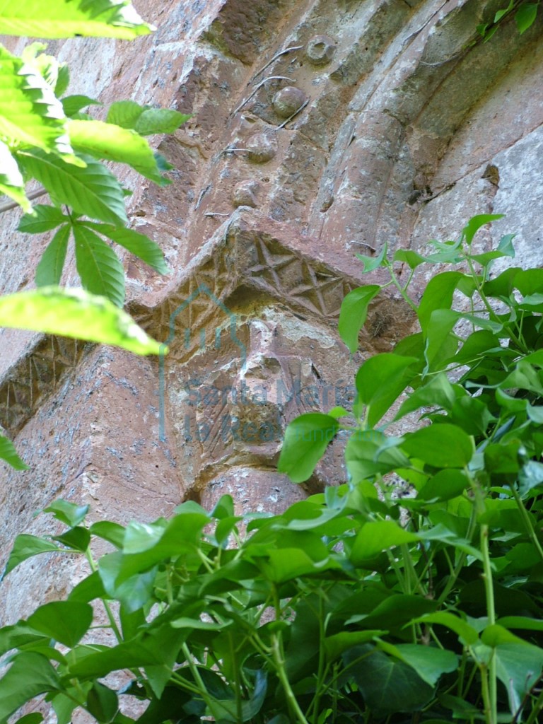 Detalle de la aspillera del ábside, en el que se observan la decoración con bolas. El cimacio esta decorado con estrellas de cuatro puntas