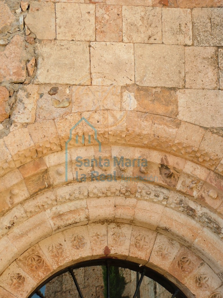 Crismón dentro de un círculo que remata la portada occidental en las arquivoltas superiores del arco