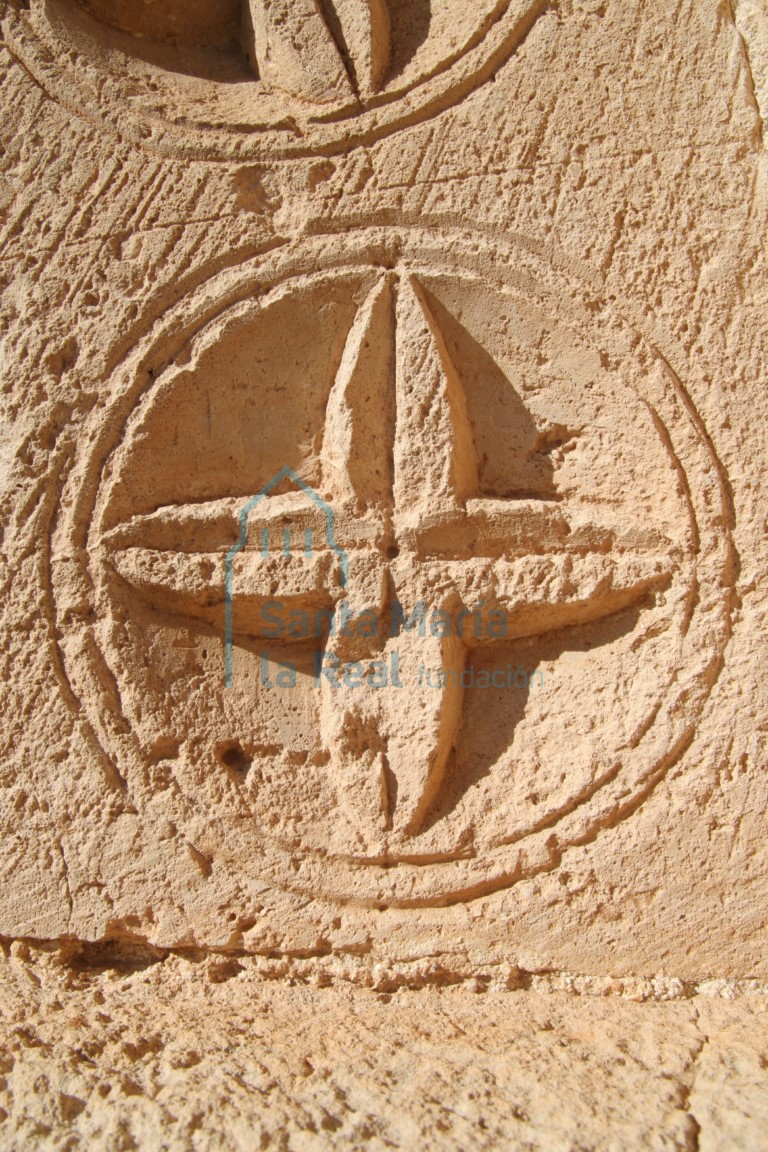 Detalle de una roseta tetrapétalas inscrita en clípeo en el arco de la portada
