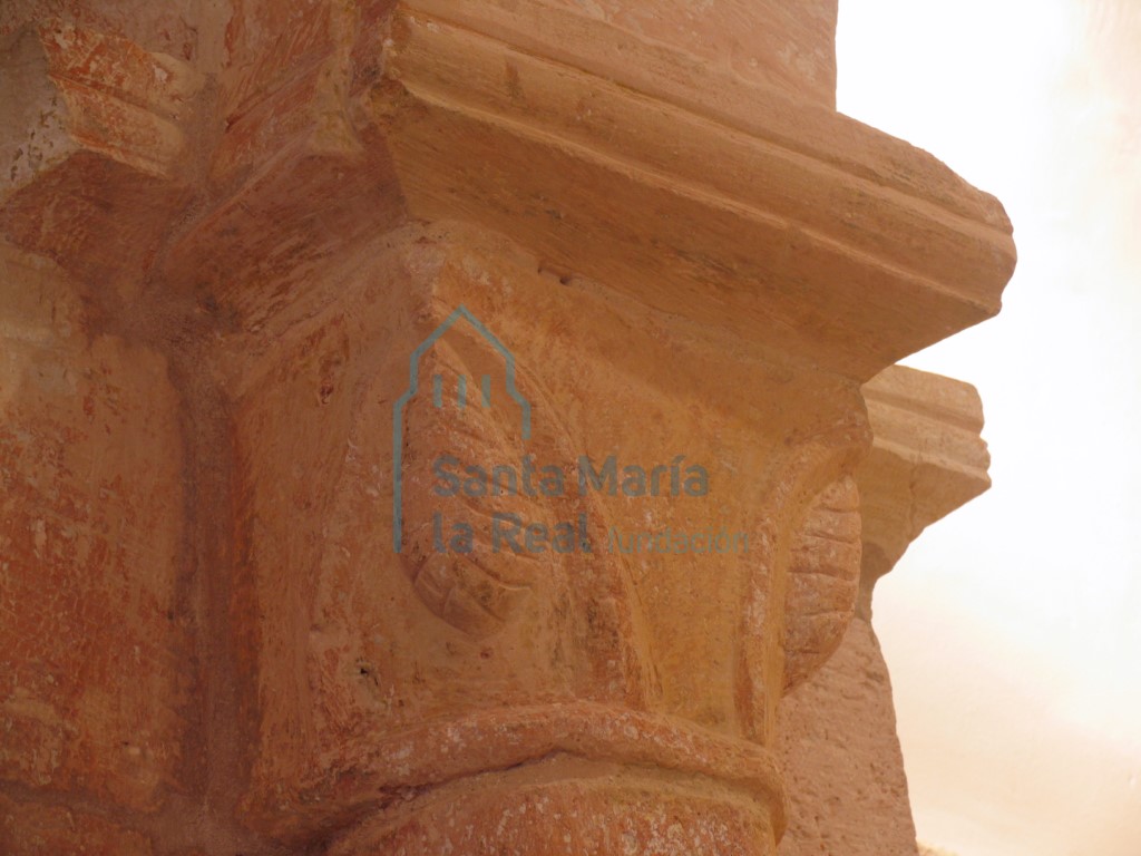 Capitel izquierdo con dos hojas que acogen unas piñas, del arco triunfal