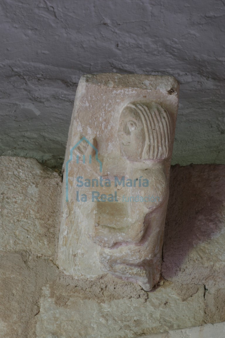 Canecillo de la portada con personaje masculino arrodillado