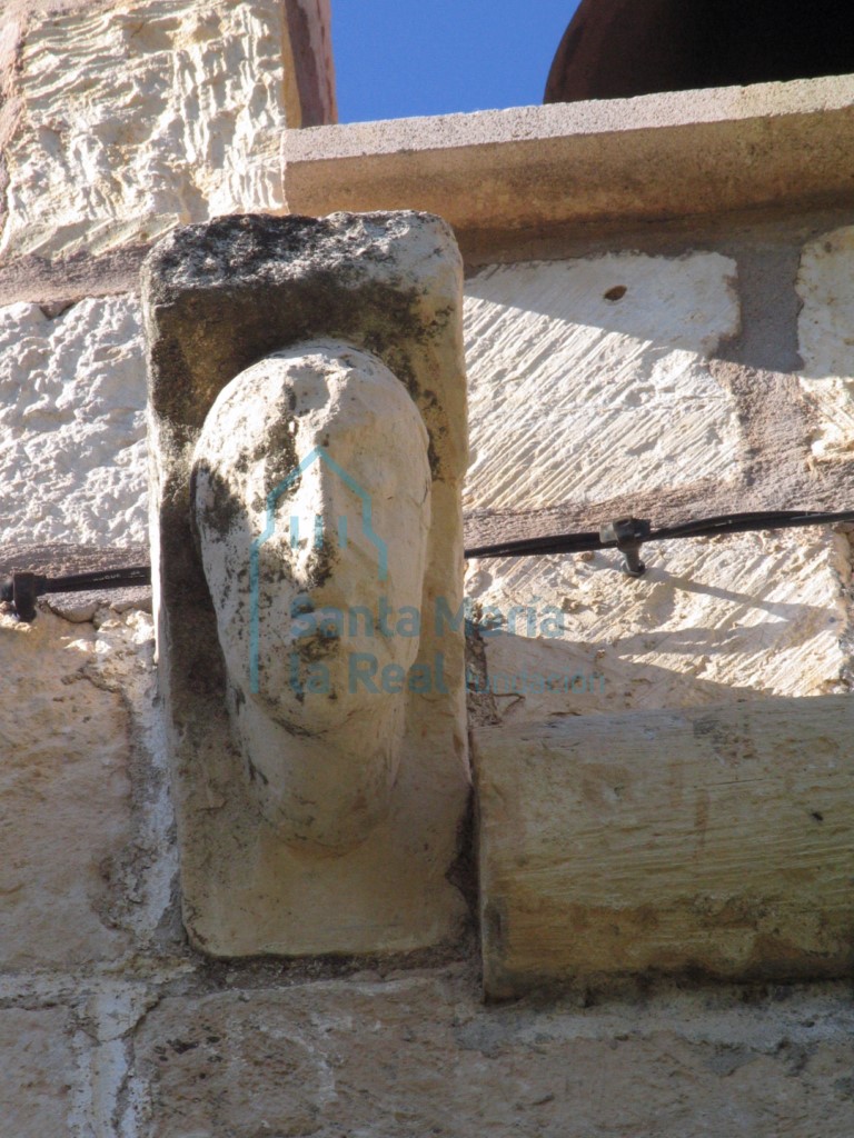Canecillo con cabeza humana sobre la puerta de acceso en la fachada meridional