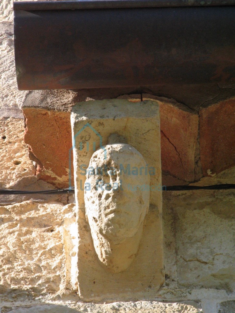 Canecillo con cabeza humana sobre la puerta de acceso en la fachada meridional