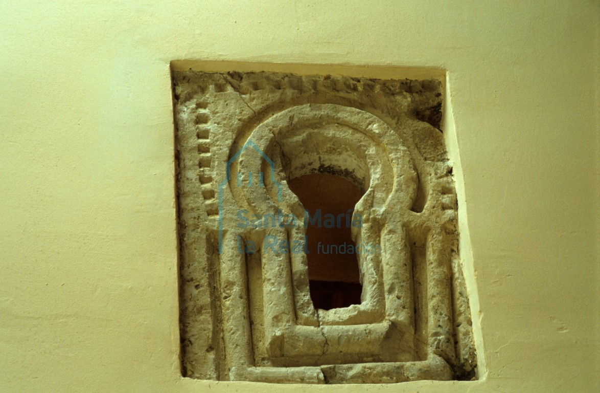 Ventana tallada en un bloque de caliza, mostrando arco de herradura trasdosado de molduras, en la parte superior del muro sur