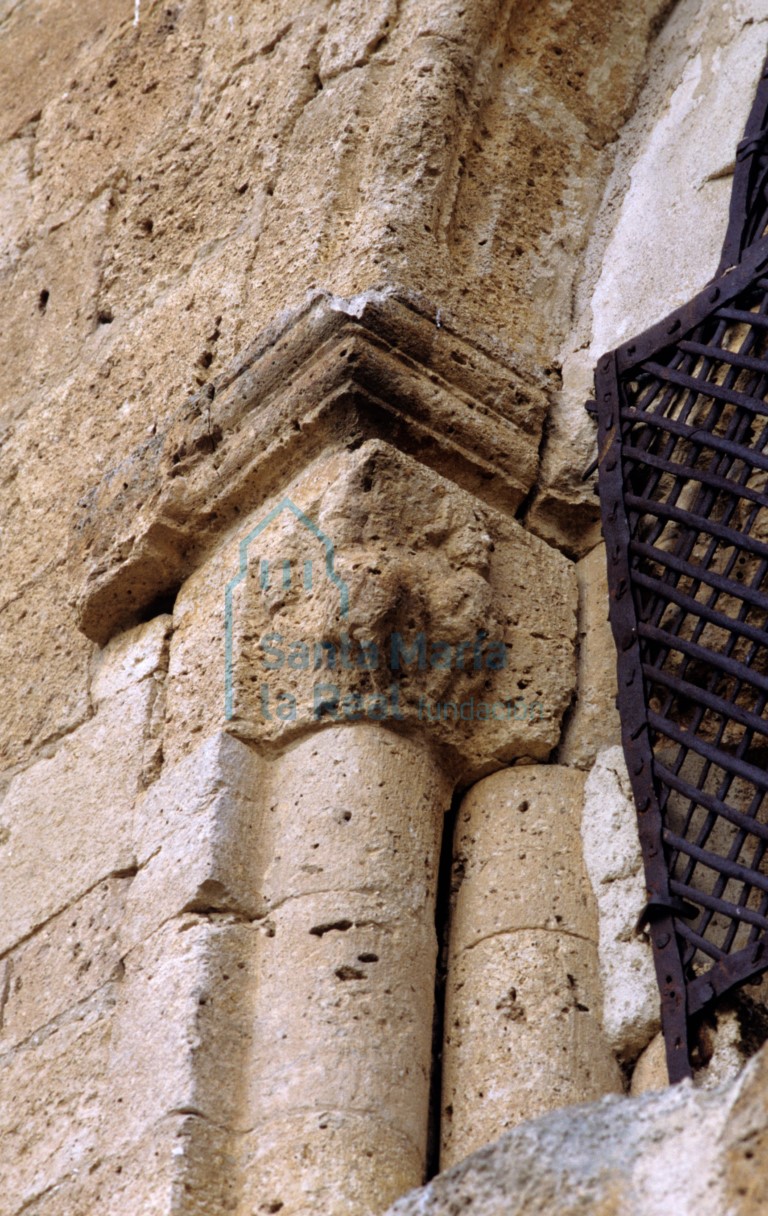 Capitel del lado izquierdo de la ventana del muro este de la cabecera. Tres rostros humanos. La figura central lleva al parecer un gorro frigio en la cabeza, tiene el cuerpo lleno de plumas que asemejan alas y se apoya en patas (pudiera ser una arpía)