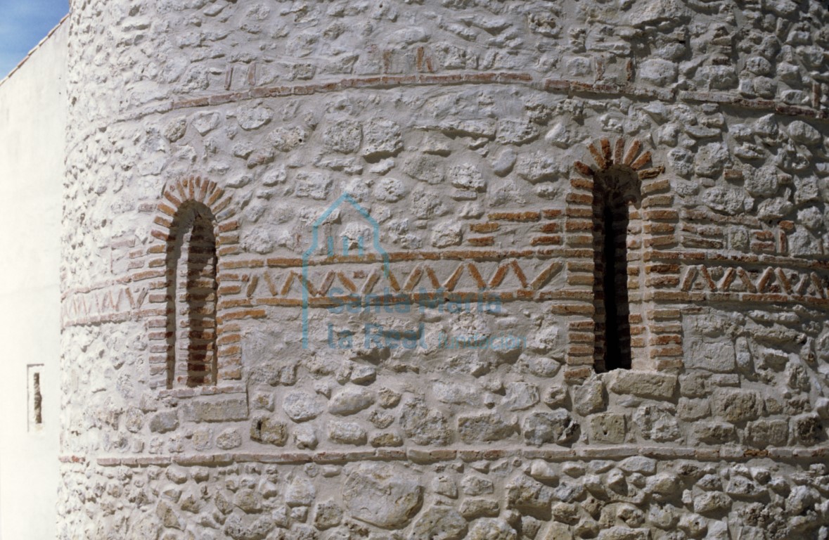 Ventanas saeteras del ábside entre las que discurre una banda decorativa enmarcada en forma de zig-zag Ventanas saeteras del ábside entre las que discurre una banda decorativa enmarcada en forma de zig-zag