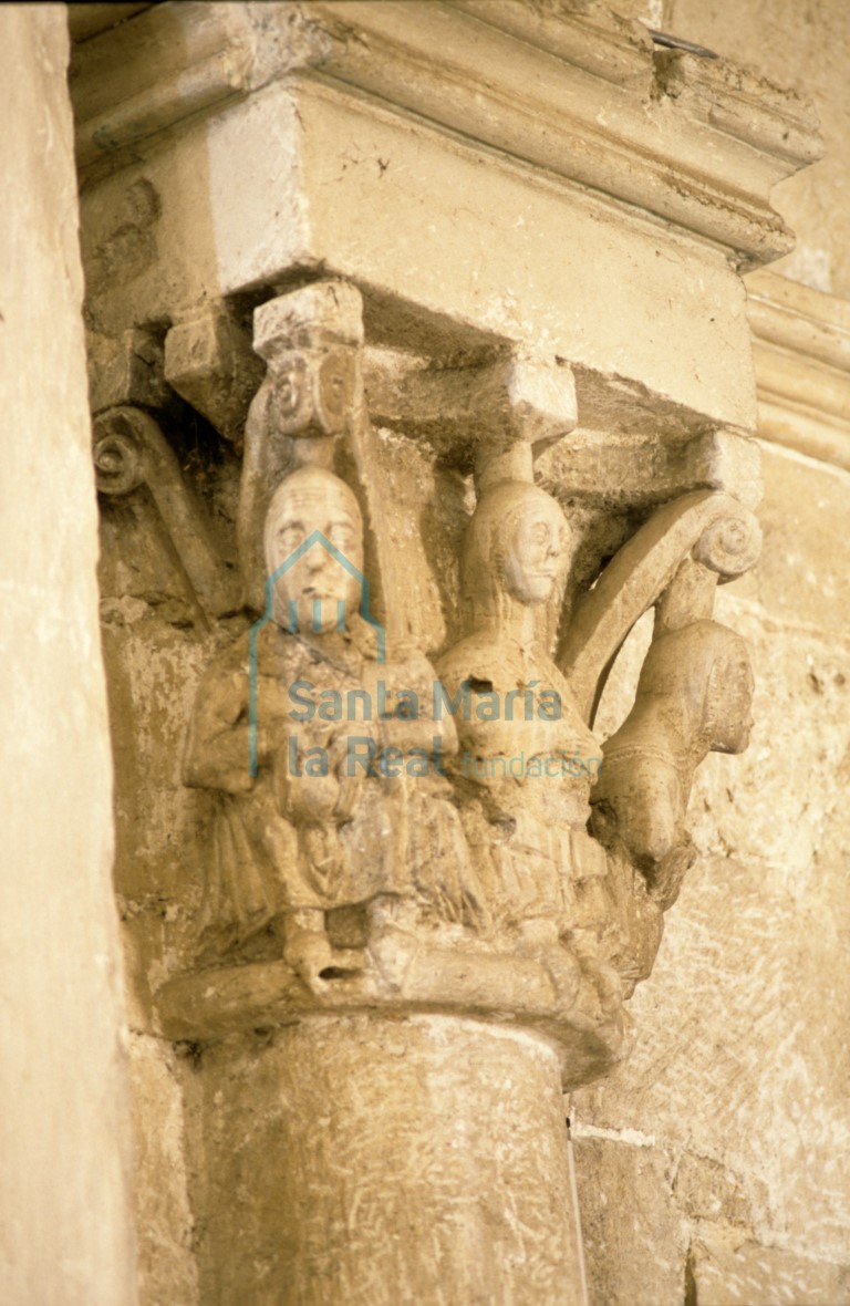 Capitel del lado del evangelio en el arco triunfal del absidiolo sur. Tres figuras femeninas sedentes, vestidas con túnica y toca, adaptadas al marco y sosteniendo entre sus manos un objeto irreconocible