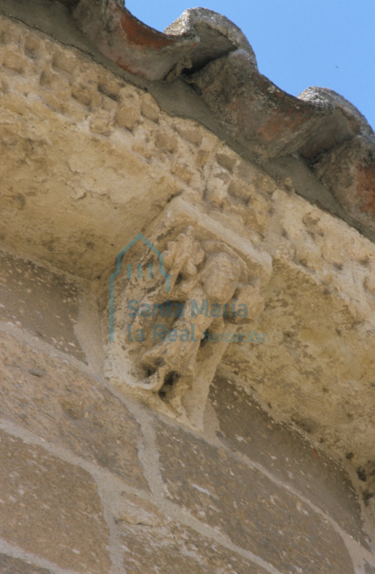 Canecillo de la cabecera. Figura masculina sosteniendo ramos con flores treboladas (abril)
