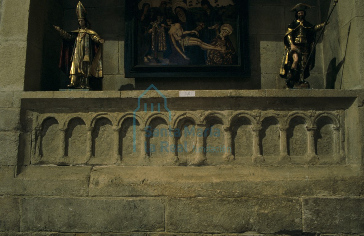 Frente de sarcófago decorado con once arcos de medio punto con chambrana en el muro norte de la nave del evangelio