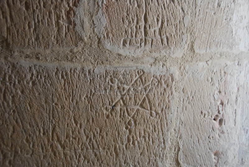 Marca de cantero en el muro exterior del claustro